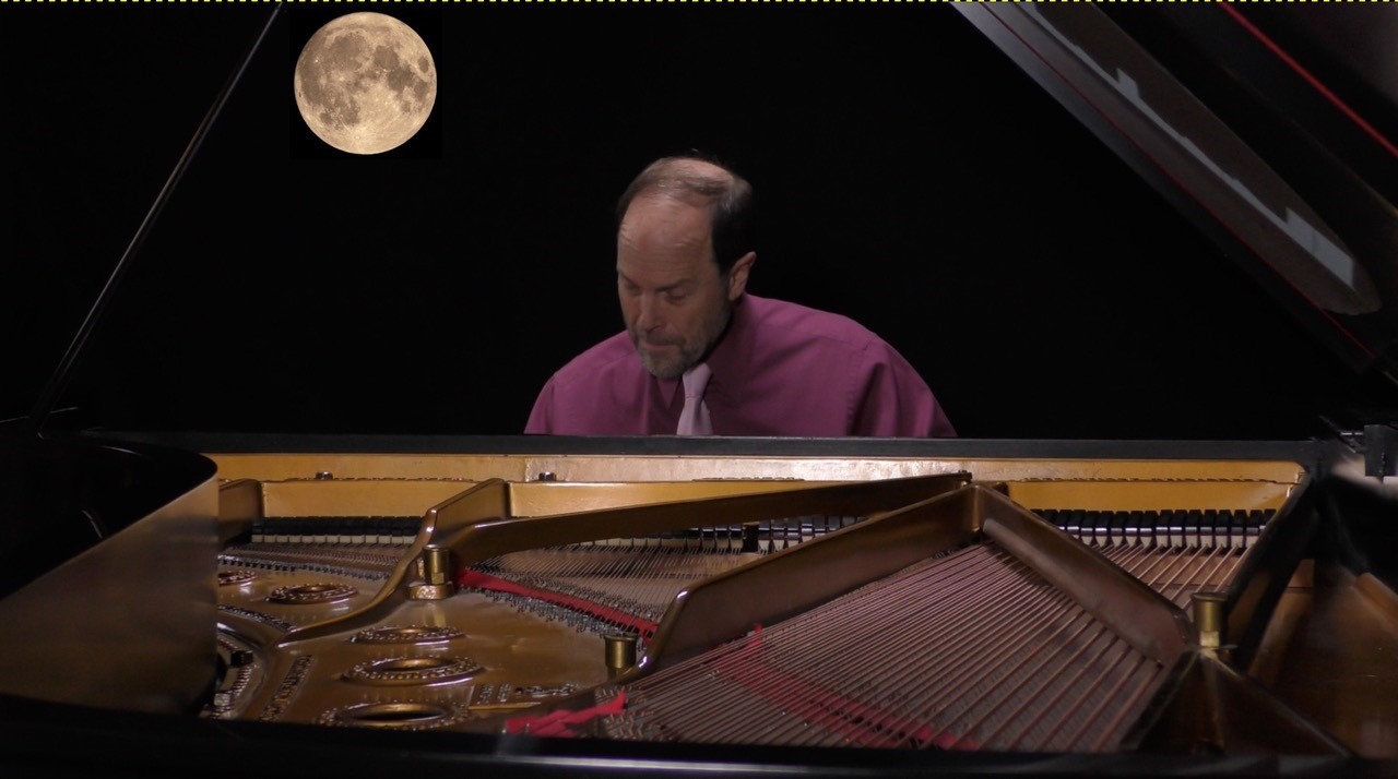 Pianist Frederick sitting at the piano with the moon over his shoulder