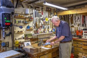 An elderly man doing woodwork in a workshop