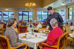 Two elderly women being served their dinner by a chef in the dining area